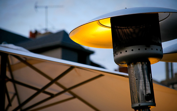 close up of a patio heater with an umbrella in the background