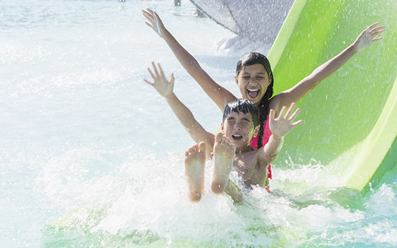 Two children splashing into the water at the end of a water slide